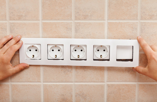 Male Hands Finishing Mounting An Electrical Wall Socket