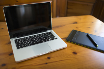 Laptop and graphic tablet on wood table.