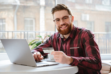 Bearded young man holding debit card.