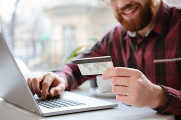 Cropped picture of cheerful bearded young man holding debit card.