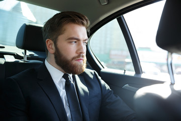 Man in suit sitting at the back seat of car