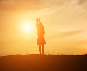 Silhouette of woman praying over beautiful sky background