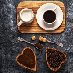 Coffee cup, beans and ground powder on stone background.