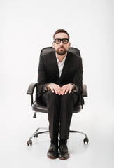 Serious businessman over white background sitting on chair.