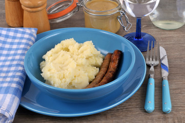 Assiette avec des chipolatas et de la purée de pommes de terre à côté d'un pot de moutarde