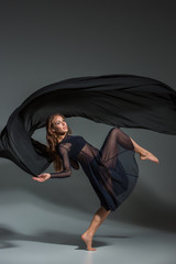 Dancing woman in a black dress. Contemporary modern dance on a gray background.