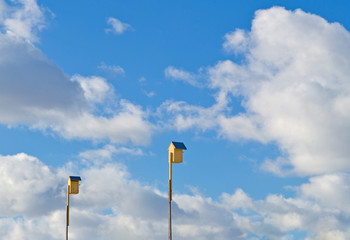 Two yellow birdhouses on the blue sky background