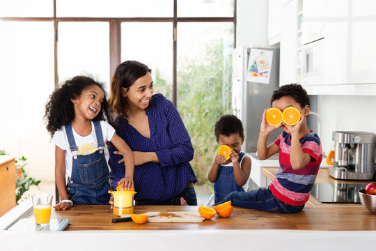 Famille qui joue dans la cuisine en préparant du jus d'orange