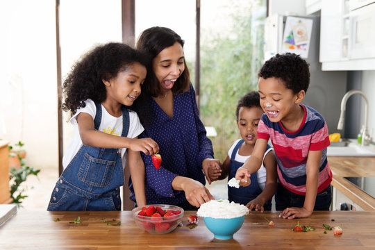 Famille qui mange des fraises et de la chantilly dans la cuisine