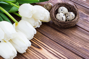 Bouquet white  tulip flowers with easter eggs on old wooden table. Place for text.