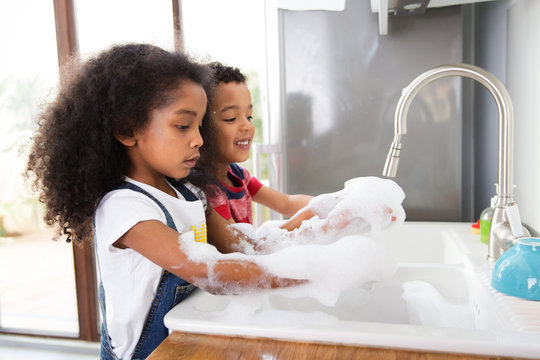 Deux enfants font la vaisselle dans la cuisine