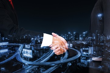 Double exposure of businessman handshake, business concept, successful business meeting on night city background, color tone effect.