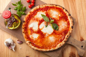 Pizza with tomato and mozzarella on a cutting board.