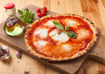 Pizza with tomato and mozzarella on a cutting board.