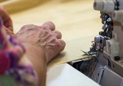 Hands of a woman who works on the sewing machine