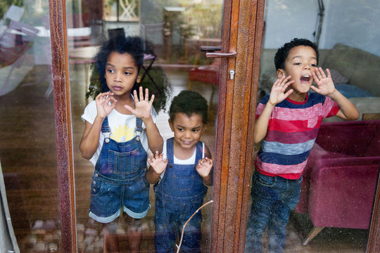 Trois enfants regardent dehors par la fen&ecirc;tre du salon
