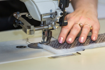 Hands of a woman who works on the sewing machine