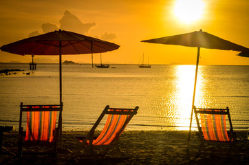 striped beachchairs and sunshade at sunset