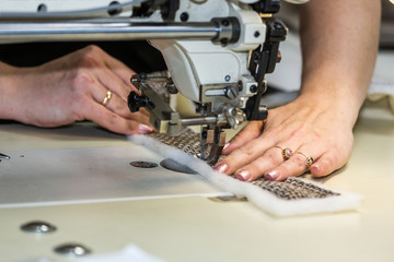 Hands of a woman who works on the sewing machine