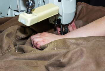 Hands of a woman who works on the sewing machine