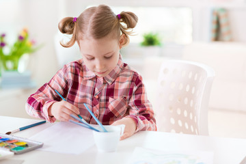 Pretty little child girl painting with colorful paint at home