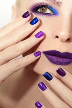 Blue purple fashion multicolored manicure and makeup on a woman in closeup.