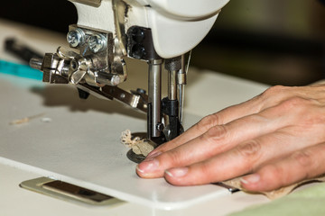Hands of a woman who works on the sewing machine