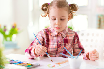 Pretty little child girl painting with colorful paint at home