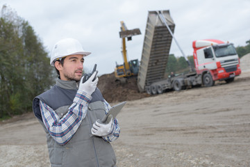 Man on construction site talking into walkie talkie