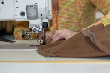Hands of a woman who works on the sewing machine