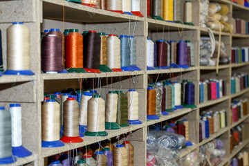 Spools of thread which are on the shelves and the loom