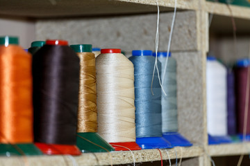 Spools of thread which are on the shelves and the loom