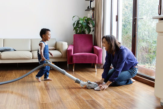 Un enfant passe l'aspirateur en jouant avec sa m&egrave;re