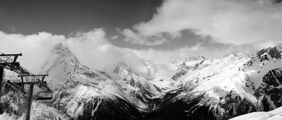 Black and white panoramic view on snow mountains in clouds