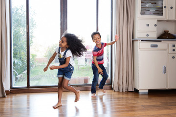 Un frère et une soeur dansent devant la fenêtre du salon