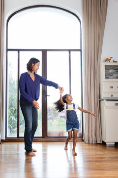 Une m&egrave;re fait danser son enfant devant la fen&ecirc;tre du salon