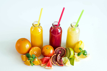 Freshly squeezed juice from citrus fruits in bottles on white background