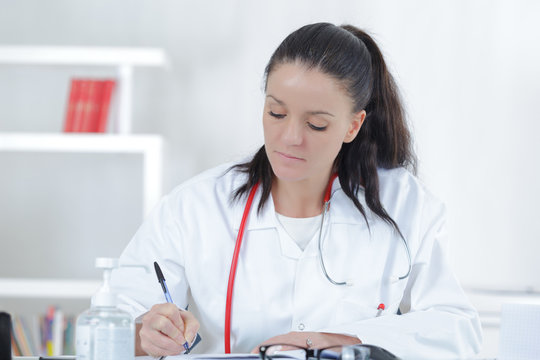 portrait of young female doctor sitting at desk in hospital