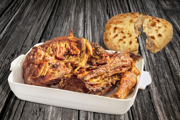 Roasted Lamb Shoulder in Porcelain Casserole with Pitta Bread Halves Set on Old Weathered Cracked Wooden Table Surface