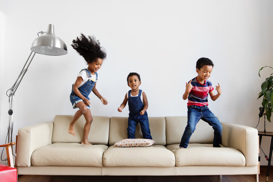 Trois enfants dansent sur le canapé du salon