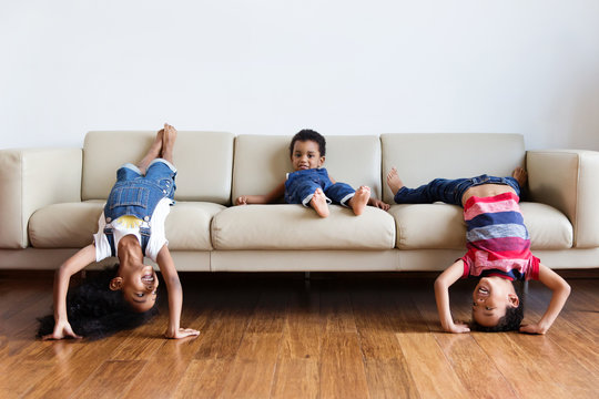 Des enfants s'amusent sur le canap&eacute; du salon la t&ecirc;te &agrave; l'envers