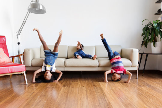 Trois enfants jouent sur le canap&eacute; du salon et se mettent &agrave; l'envers