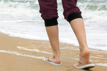 the girl's legs walking on the beach