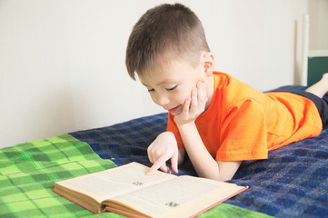 children education, boy reading book lying on bed, child portrait smiling with book, education concept, interesting storybook