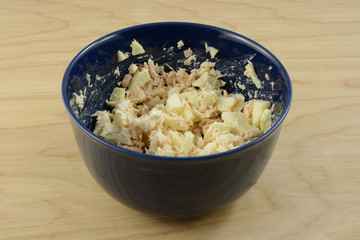 Tuna salad with chopped apple in blue bowl on table