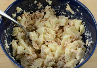 Close up of tuna salad with chopped apple in blue bowl on table