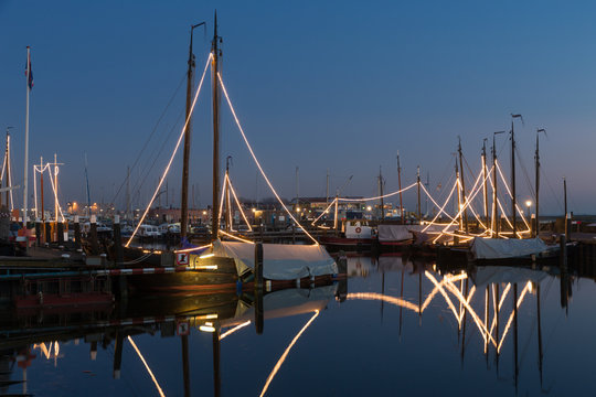 Illuminated traditional wooden fishing ships at night in Dutch harbor