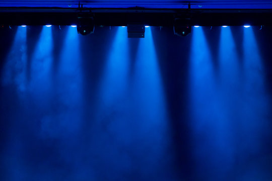 The blue light from the spotlights through the smoke in the theatre during the performance. Lighting equipment.