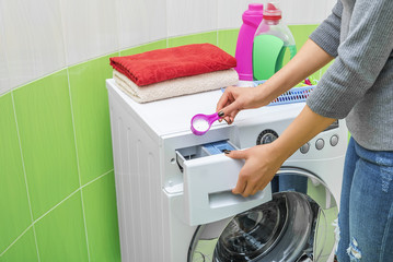 Woman throws laundry detergent into the washing machine.