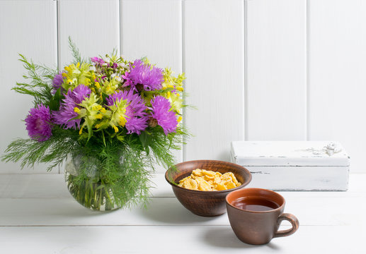 Flowers bouquet in vase with cup tea and corn flakes